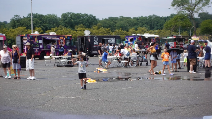 Food truck festival with people enjoying gourmet food trucks, unique eats on wheels, and outdoor games.