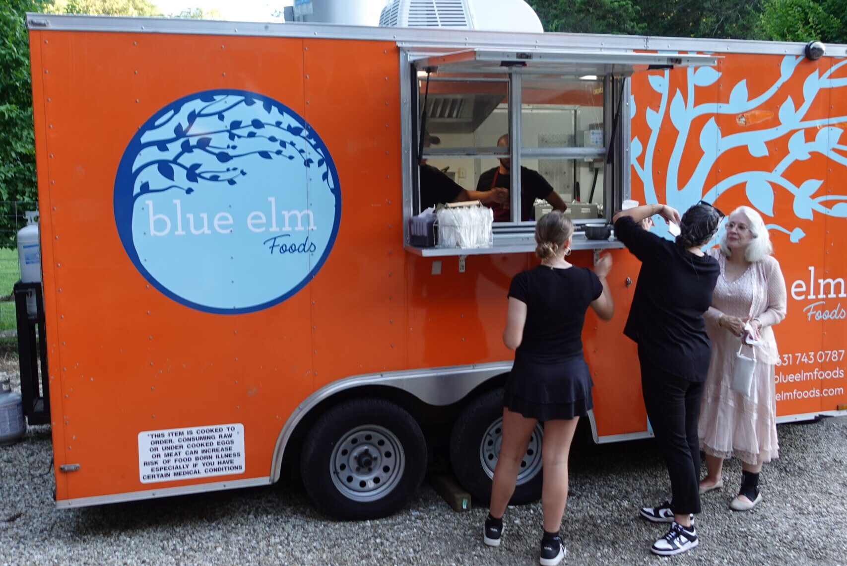 Orange food truck serving customers, ideal for gourmet food truck road trips and local mobile food services.